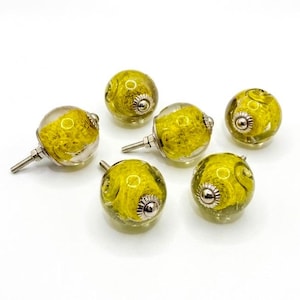 May include: Six spherical cabinet knobs featuring a clear glass exterior and a bright yellow textured interior. Each knob has a silver-toned metal base and a threaded metal screw extending from the back for installation on furniture or cabinetry.