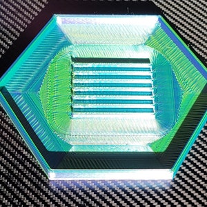 May include: A hexagonal, iridescent green and blue plastic tray with a rectangular, ridged opening in the center.