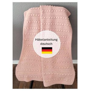 May include: A soft pink crocheted blanket featuring a textured pattern of horizontal rows and small raised bobble stitches. A circular white overlay in the center displays the text Häkelanleitung deutsch above a German flag icon.