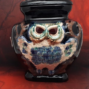 May include: A black ceramic owl jar with a blue and white owl design. The jar has a lid with a small owl finial.