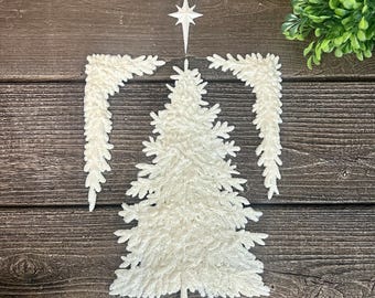 May include: A white, textured, flat-lay Christmas tree decoration set featuring a central pine tree shape, two matching angled branch pieces, a small star topper, and a cloud-like accent piece, all arranged symmetrically on a dark wood surface.