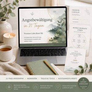 Könnte beinhalten: Ein Laptop zeigt ein beruhigendes Landschaftsbild mit dem deutschen Text: "Angstbewältigung in 21 Tagen". Daneben befinden sich gedruckte Karten und ein Notizbuch mit einem goldenen Stift. Die Szene umfasst eine brennende Kerze, eine Tasse Tee und eine Vase mit Grün.