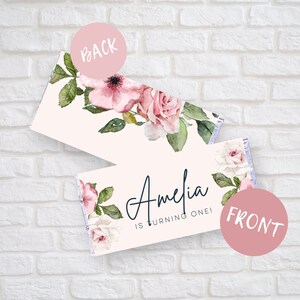 Könnte beinhalten: Rosa-weiße Blumenmuster-Schokoladentafel-Verpackung mit dem Text "Amelia wird ein Jahr alt!" auf der Vorderseite.