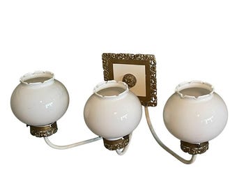 Vintage Hollywood Regency 3-lichts wandlamp met bolvormige kaptafel van melkglas en gouden filigraan.