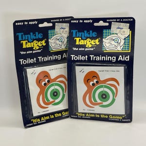 Puede incluir: Dos paquetes de ayudas para el entrenamiento para ir al baño "Tinkle Target". Cada paquete presenta un diseño azul y amarillo con el texto "Tinkle Target" y "the aim game". La pegatina del objetivo tiene un pulpo naranja y un objetivo verde.