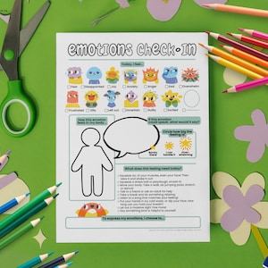 Puede incluir: Una hoja de trabajo blanca de verificación de emociones con ilustraciones coloridas de varias emociones. La hoja de trabajo incluye indicaciones para la autorreflexión, rodeada de lápices de colores, tijeras y recortes de papel sobre una superficie verde.