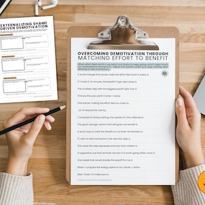 Puede incluir: Un portapapeles con el texto "OVERCOMING DEMOTIVATION THROUGH MATCHING EFFORT TO BENEFIT" y una hoja de trabajo titulada "EXTERNALIZING SHAME DRIVEN DEMOTIVATION". Una mano sostiene un l&aacute;piz y se ve un port&aacute;til.