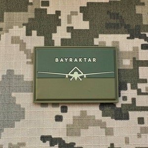 May include: A green and brown patch with the text "BAYRAKTAR" in white and a white silhouette of a drone.