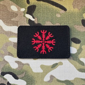 May include: A black patch with a red embroidered symbol, resembling a snowflake or a star, with eight points.