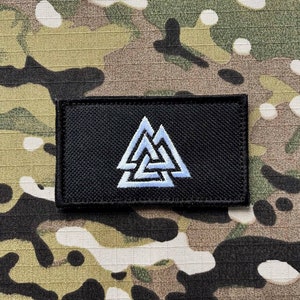 May include: Black patch with a white embroidered Valknut symbol. The patch is made of a woven fabric and has a stitched edge.
