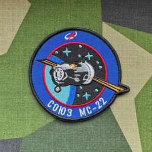 May include: A blue and black embroidered patch with a spacecraft design. The patch has a red border and the text "COH3 MC-22" in white.