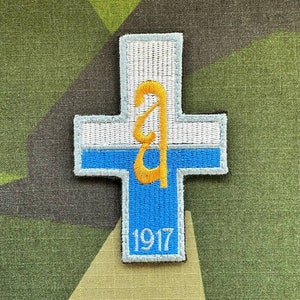 Puede incluir: Un parche bordado azul y blanco con una letra "A" amarilla y el año "1917" en blanco.