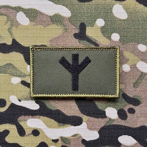 以下が含まれることがあります： 緑と黒の刺繍パッチで、黒のシンボルはスタイリッシュな木またはYの形に似ています