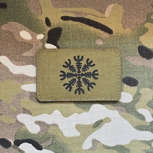 以下が含まれることがあります： 緑色の背景に黒いシンボルが刺繍された黒と緑の刺繍パッチ。シンボルは、中央に円があるスタイリッシュな8角形星です。