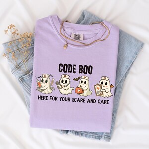 nurse Halloween Comfort Colors shirt that has 4 spooky nurses reading Code Boo: here for your scare and care for er nurse or nightshift nurse in the color orchid purple