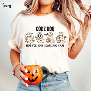 nurse Halloween Comfort Colors shirt that has 4 spooky nurses reading Code Boo: here for your scare and care for er nurse or nightshift nurse in the color ivory