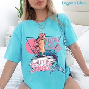 salty mermaid shirt with a retro summer vibe of mermaid that says A Little Salty A Little Sweet on a Comfort Colors shirt in the color blossom lagoon blue