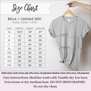 May include: A light gray Bella + Canvas 3001 unisex jersey t-shirt hanging on a wooden hanger. The image includes a size chart with measurements in inches for width, chest, and length, ranging from XS to 5XL. Care instructions are also listed.