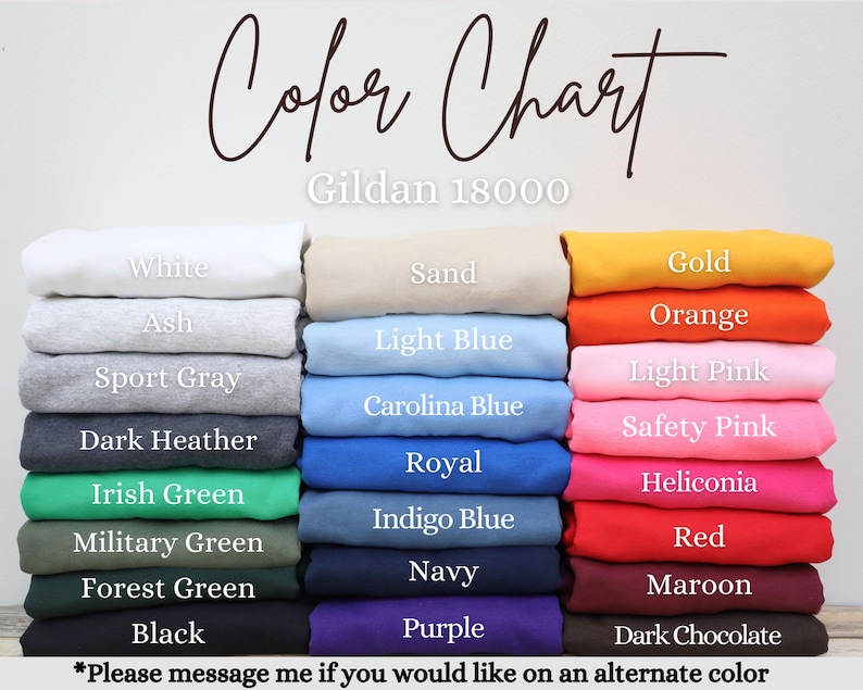 May include: A colour chart for Gildan 18000 sweatshirts featuring three vertical stacks of folded garments in various colours. Labels include White, Ash, Sport Gray, Dark Heather, Irish Green, Military Green, Forest Green, Black, Sand, Light Blue, Carolina Blue, Royal, Indigo Blue, Navy, Purple, Gold, Orange, Light Pink, Safety Pink, Heliconia, Red, Maroon, and Dark Chocolate.
