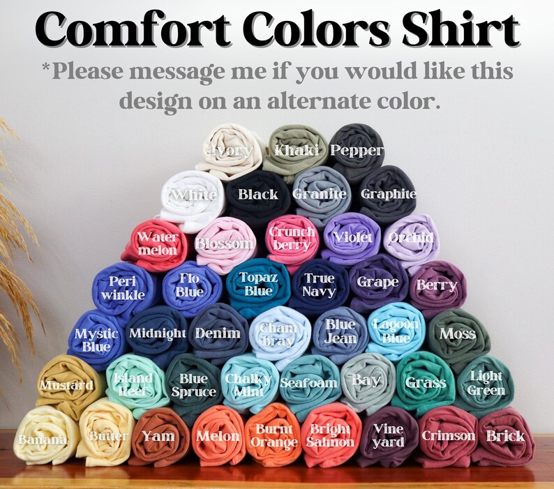 May include: A display of rolled Comfort Colors shirts in various colors, including white, black, and blue. The text at the top reads "Comfort Colors Shirt." Additional text encourages inquiries about alternate colors.