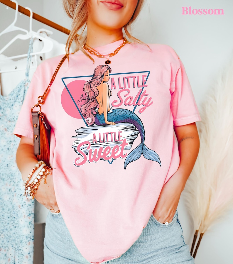 salty mermaid shirt with a retro summer vibe of mermaid that says A Little Salty A Little Sweet on a Comfort Colors shirt in the color blossom blossom pink