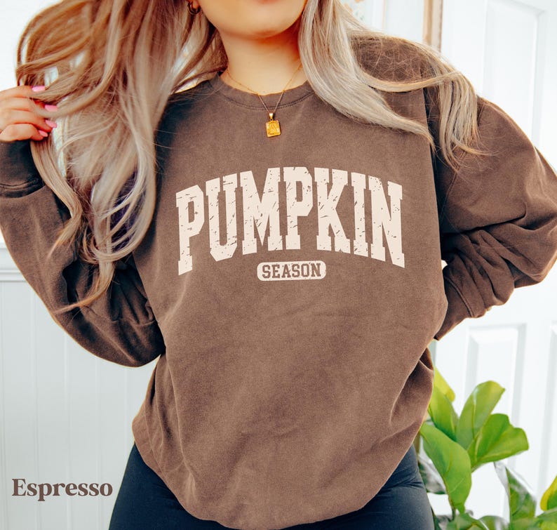 Puede incluir: Sudadera color espresso con el texto "PUMPKIN SEASON" en blanco, con una fuente de estilo universitario. La sudadera tiene cuello redondo y mangas largas. El estilo general es informal y c&oacute;modo.