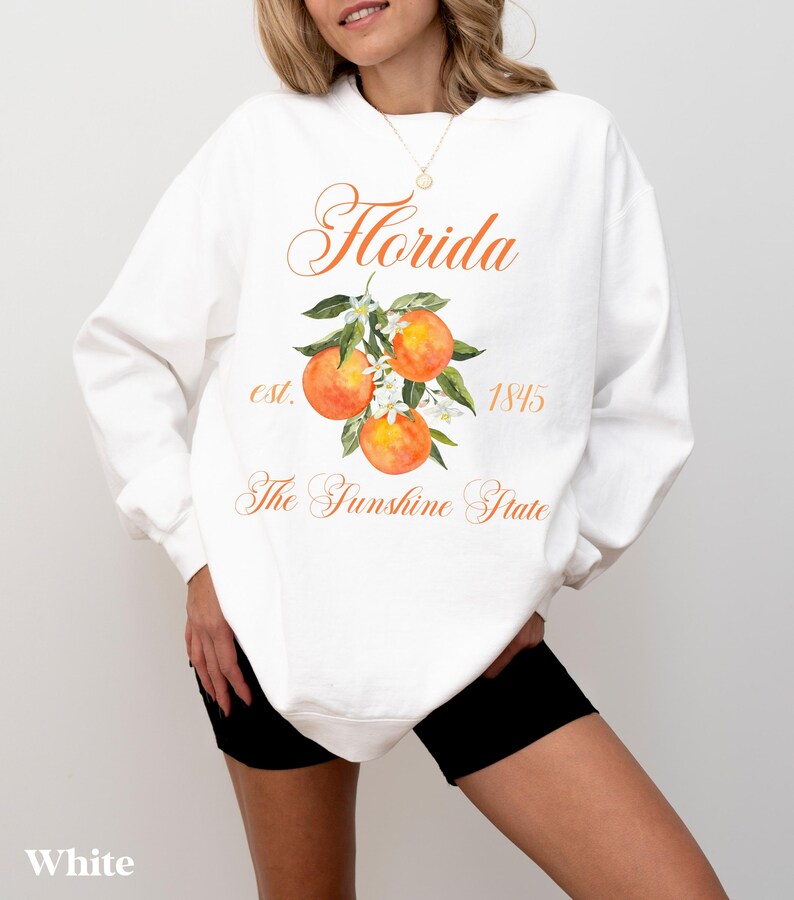 Florida sweatshirt that has a floral orange design saying Florida The Sunshine State est. 1845 on a summer crewneck Comfort Colors sweatshirt in the color white