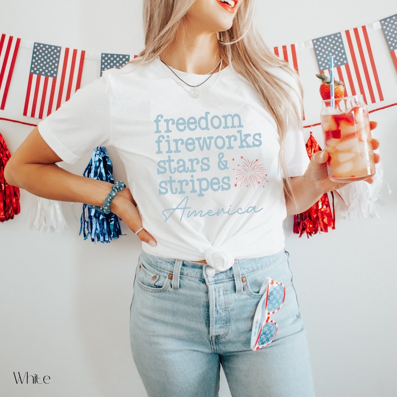 America fourth of July shirt that says freedom fireworks stars & stripes America with a firework on a Bella Canvas shirt in the color white