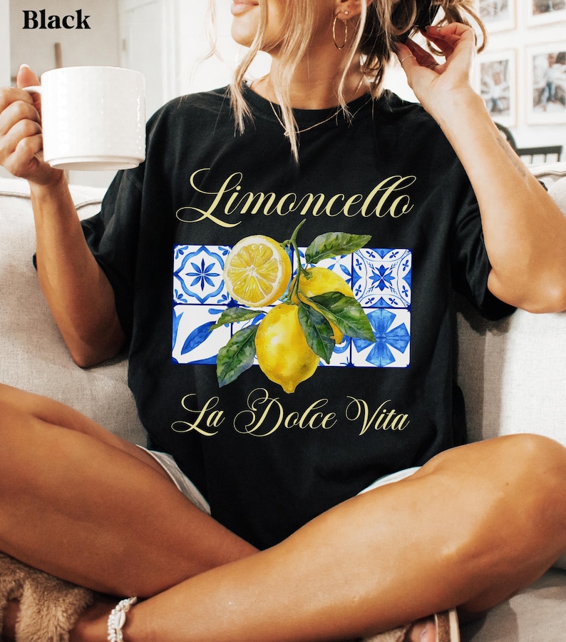 Pu&ograve; includere: Maglietta nera con una grafica di limone e il testo "Limoncello La Dolce Vita" in un font bianco corsivo.