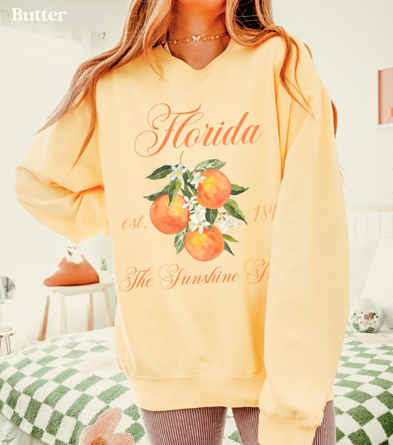 Florida sweatshirt that has a floral orange design saying Florida The Sunshine State est. 1845 on a summer crewneck Comfort Colors sweatshirt in the color butter yellow