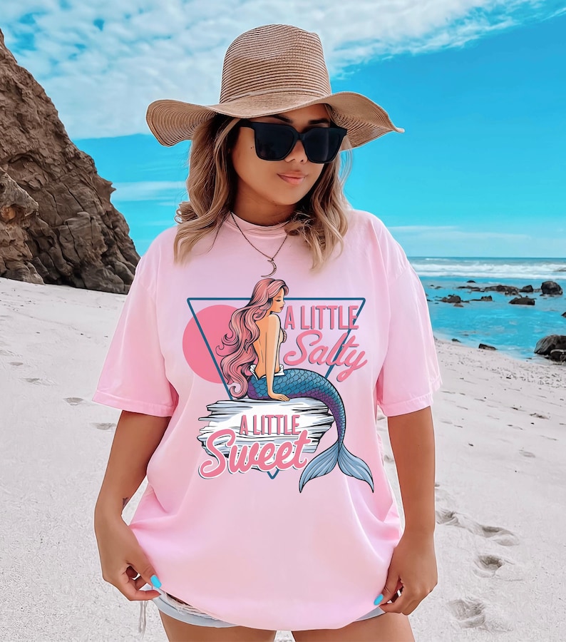 salty mermaid shirt with a retro summer vibe of mermaid that says A Little Salty A Little Sweet on a Comfort Colors shirt in the color blossom light pink