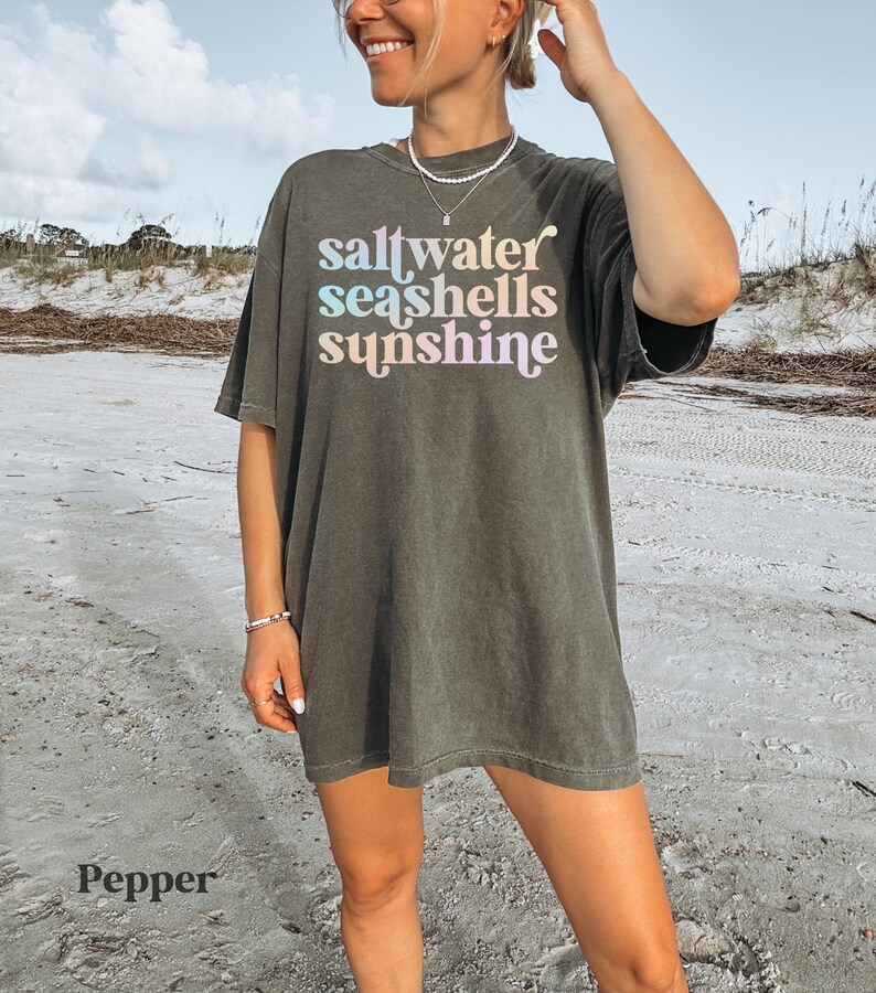 sunshine beach vacation shirt that says saltwater seashells sunshine in a fun summer print on a Comfort Colors shirt in the color pepper