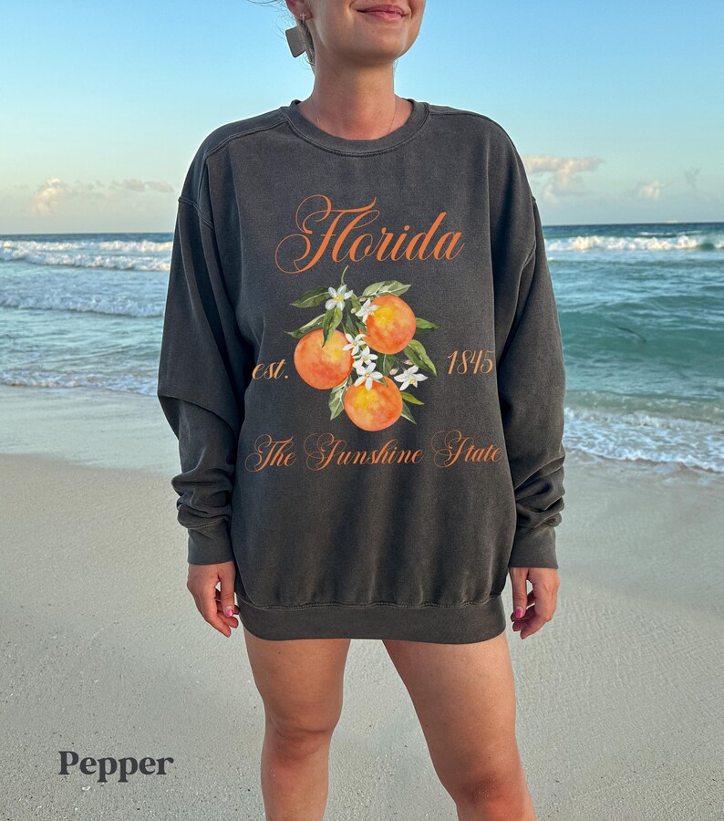 Florida sweatshirt that has a floral orange design saying Florida The Sunshine State est. 1845 on a summer crewneck Comfort Colors sweatshirt in the color pepper
