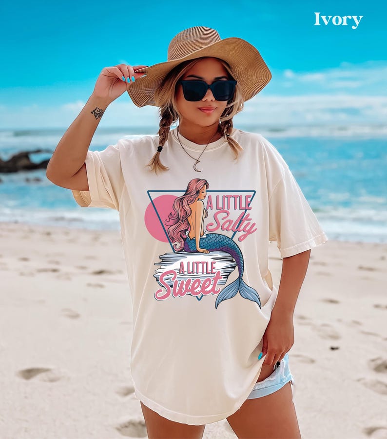 salty mermaid shirt with a retro summer vibe of mermaid that says A Little Salty A Little Sweet on a Comfort Colors shirt in the color blossom ivory
