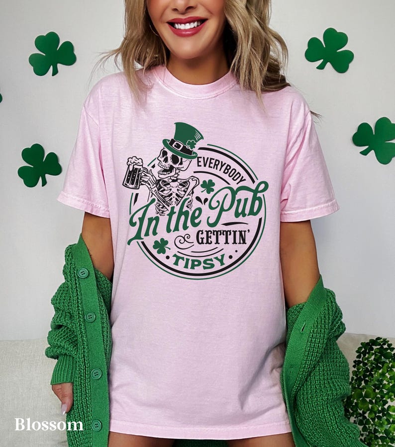 skeleton pub crawl shirt for your St. Patrick's Day party that has a skeleton holding a beer wearing a green Leprechaun hat with shamrocks saying Everybody in the Pub Gettin' Tipsy on a Comfort Colors shirt in the color blossom pink