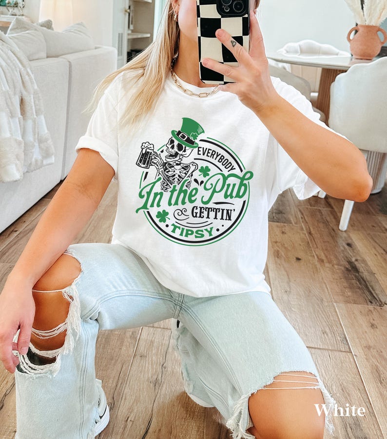 skeleton pub crawl shirt for your St. Patrick's Day party that has a skeleton holding a beer wearing a green Leprechaun hat with shamrocks saying Everybody in the Pub Gettin' Tipsy on a Comfort Colors shirt in the color white