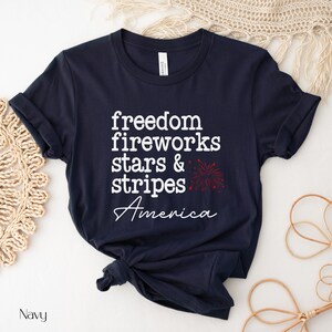America fourth of July shirt that says freedom fireworks stars & stripes America with a firework on a Bella Canvas shirt in the color navy blue