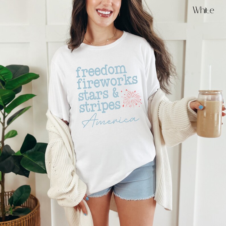 America fourth of July shirt that says freedom fireworks stars & stripes America with a firework on a Bella Canvas shirt in the color white