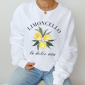 May include: White sweatshirt with a graphic of lemons and the text "Limoncello la dolce vita".