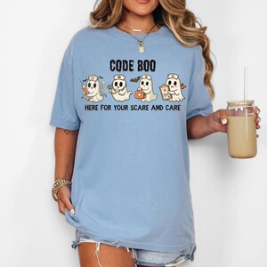 nurse Halloween Comfort Colors shirt that has 4 spooky nurses reading Code Boo: here for your scare and care for er nurse or nightshift nurse in the color washed denim blue
