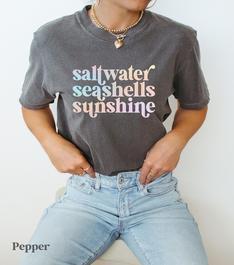 sunshine beach vacation shirt that says saltwater seashells sunshine in a fun summer print on a Comfort Colors shirt in the color pepper