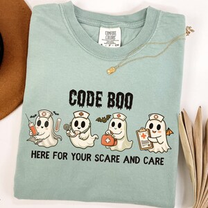 nurse Halloween Comfort Colors shirt that has 4 spooky nurses reading Code Boo: here for your scare and care for er nurse or nightshift nurse in the color bay green