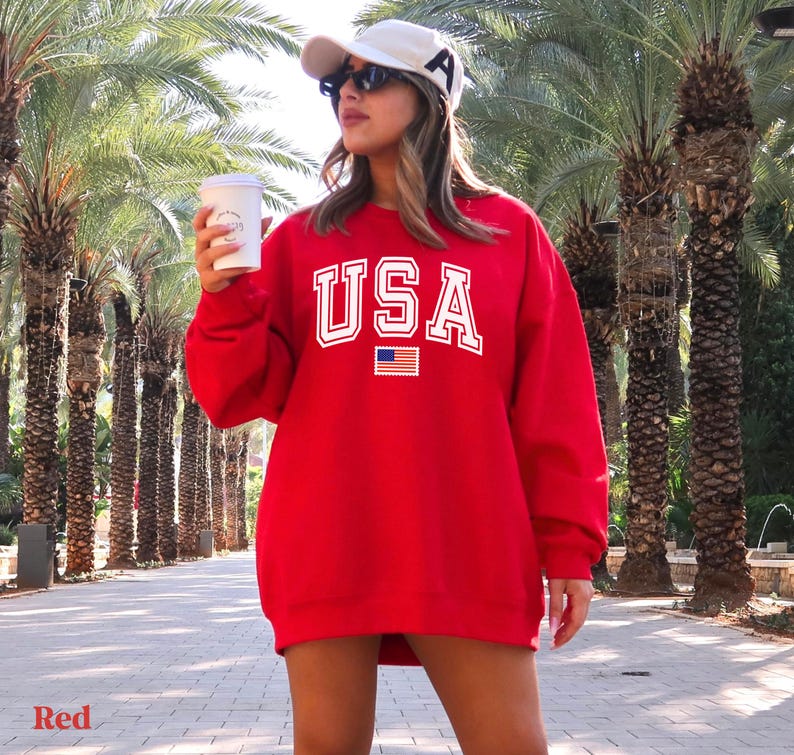 Pu&ograve; includere: Felpa rossa con scritta bianca "USA" e una piccola grafica della bandiera americana. La felpa &egrave; oversize e ha un collo rotondo.