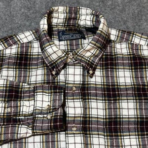 May include: A button-down flannel shirt with a classic plaid pattern in white, brown, and yellow. The shirt features a button-down collar and cuffs, with the "Lands' End" label visible. The fabric appears soft and comfortable, suitable for casual wear.