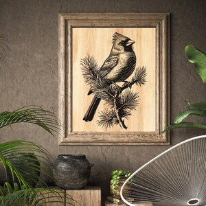 May include: A framed wood print of a black and white illustration of a cardinal perched on a branch of pine needles.