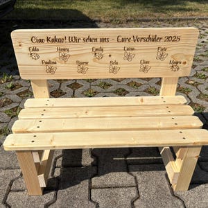 May include: A small, unfinished wooden bench with a backrest. The backrest has engraved text and names, along with butterfly and ladybug designs. The bench is constructed with visible screws and has a natural wood grain finish.