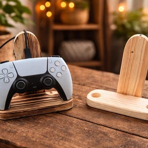 Könnte beinhalten: Ein weiß-schwarzer Videospiel-Controller liegt auf einem gebeizten Holzsockel, der mit einem Holzständer verbunden ist. Daneben befindet sich ein passender Holzständer. Der Controller hat mehrere Tasten und ein schwarzes Ladekabel.