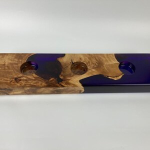 Peut inclure: Un plateau en bois avec trois indentations circulaires remplies de résine violette. Le plateau a une finition en bois naturel et une surface lisse et polie.