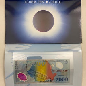 May include: A 2000 Romanian Lei banknote featuring a depiction of the 1999 solar eclipse over Romania. The banknote is blue, yellow, red, and green with the text "DOUA MII lei 2.000" and "BANCA NAŢIONALA A ROMANIEI" printed on it.