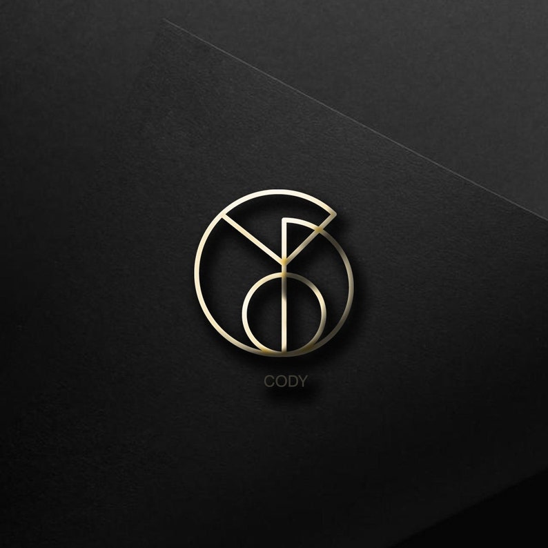 May include: A gold-colored logo with the letters "CODY" underneath. The logo is a circle with a smaller circle inside, and a line that forms a "Y" shape.